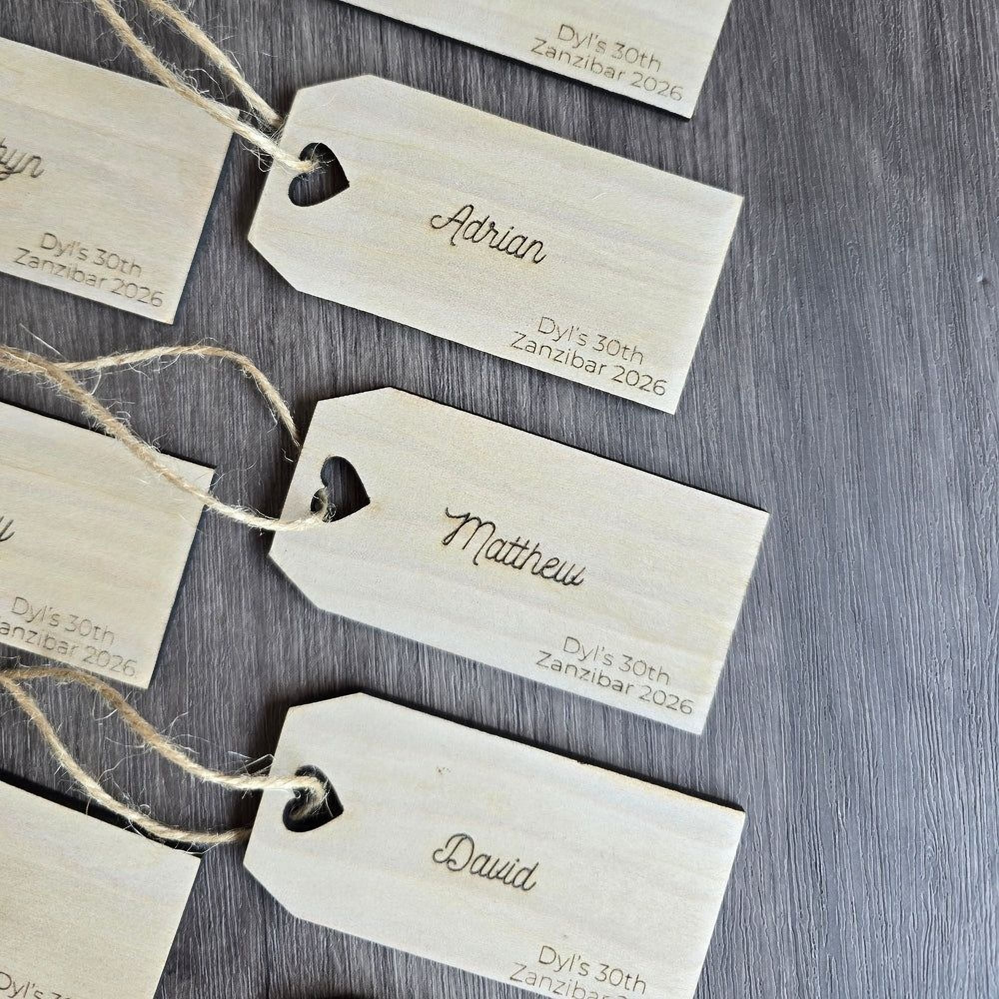 a collection of wooden name tags with names and dates printed on them, arranged on a wooden surface.