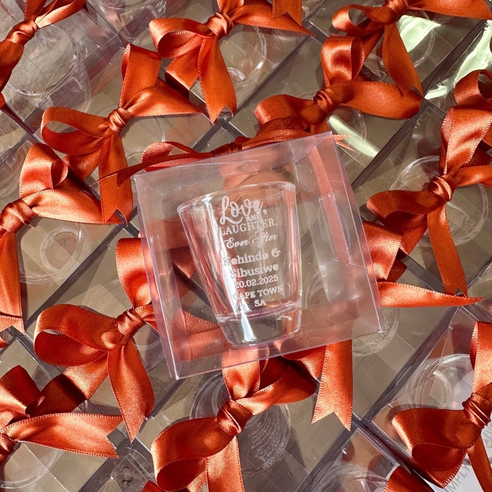 Clear glass with engraved text in a clear giftbox tied with ribbons.