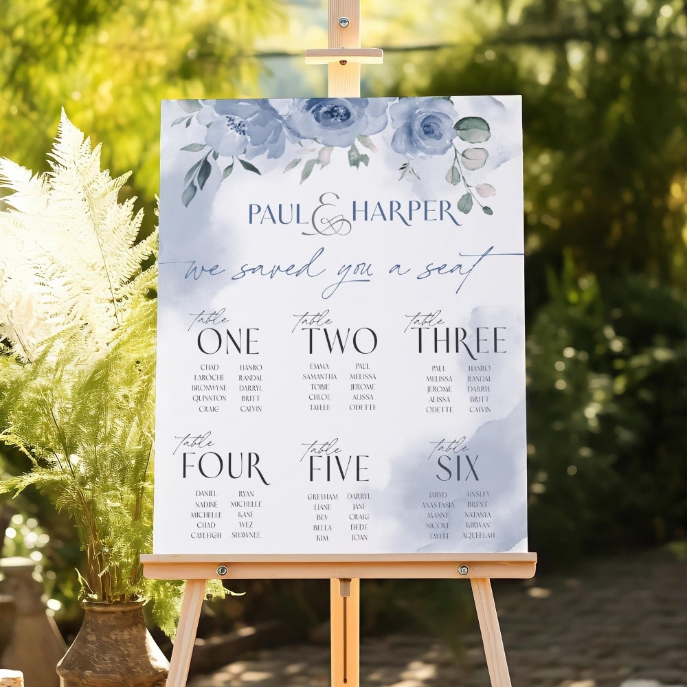 Seating chart sign for a wedding on an easel with floral design and text.