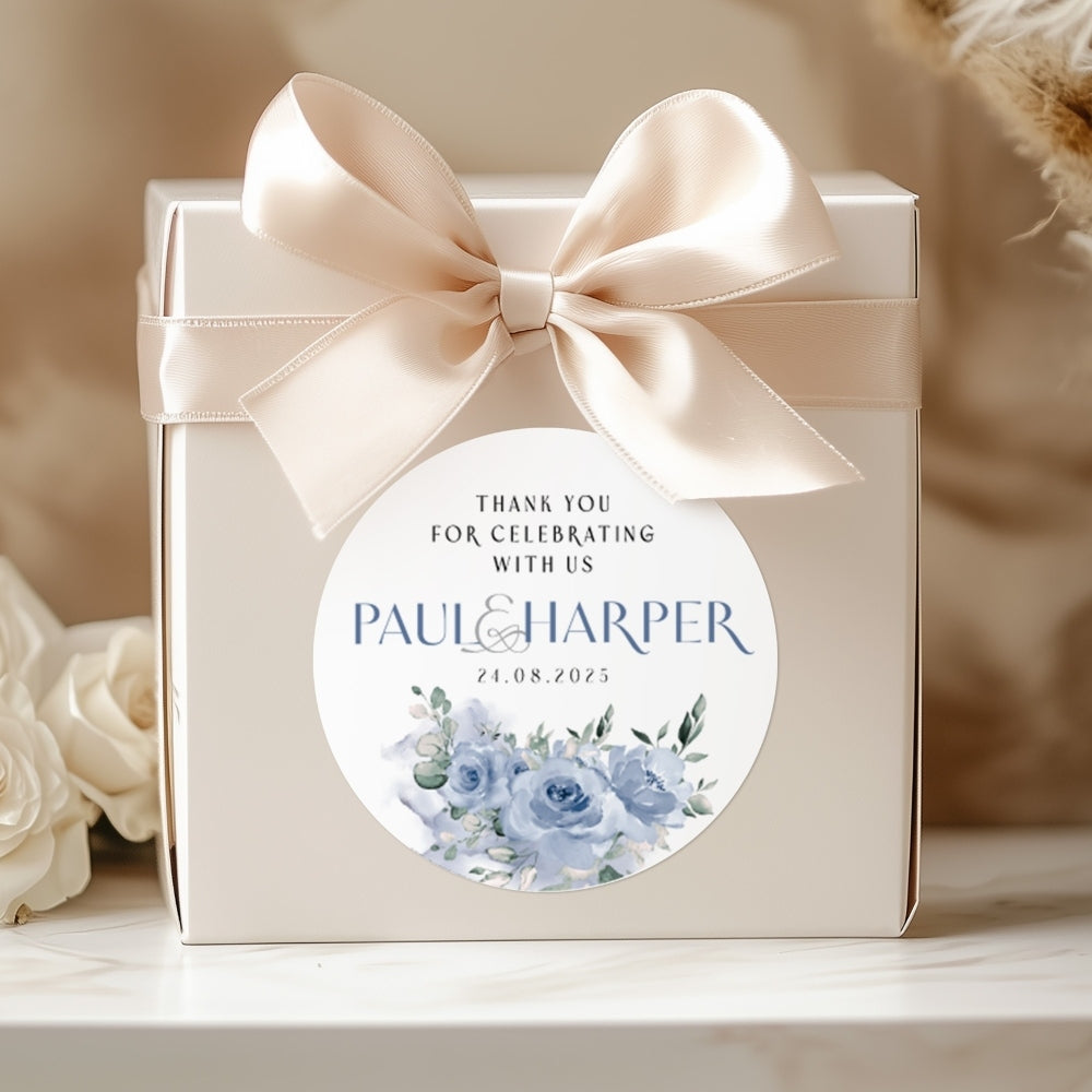 Gift box with a ribbon and personalized sticker featuring floral design and text.