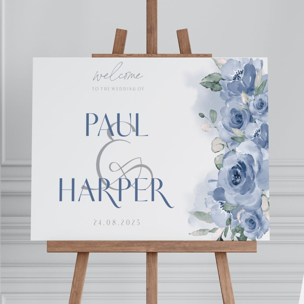 A personalized 'Welcome' sign with floral design and custom text in blue and white colors, displayed on an easel.