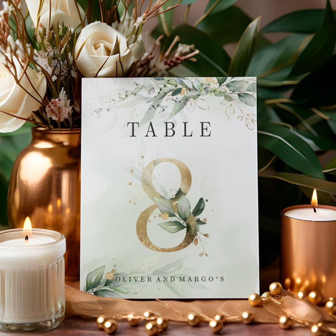 A printed table number with an elegant green botanical stationery design displayed on a table with candles and decorative elements.