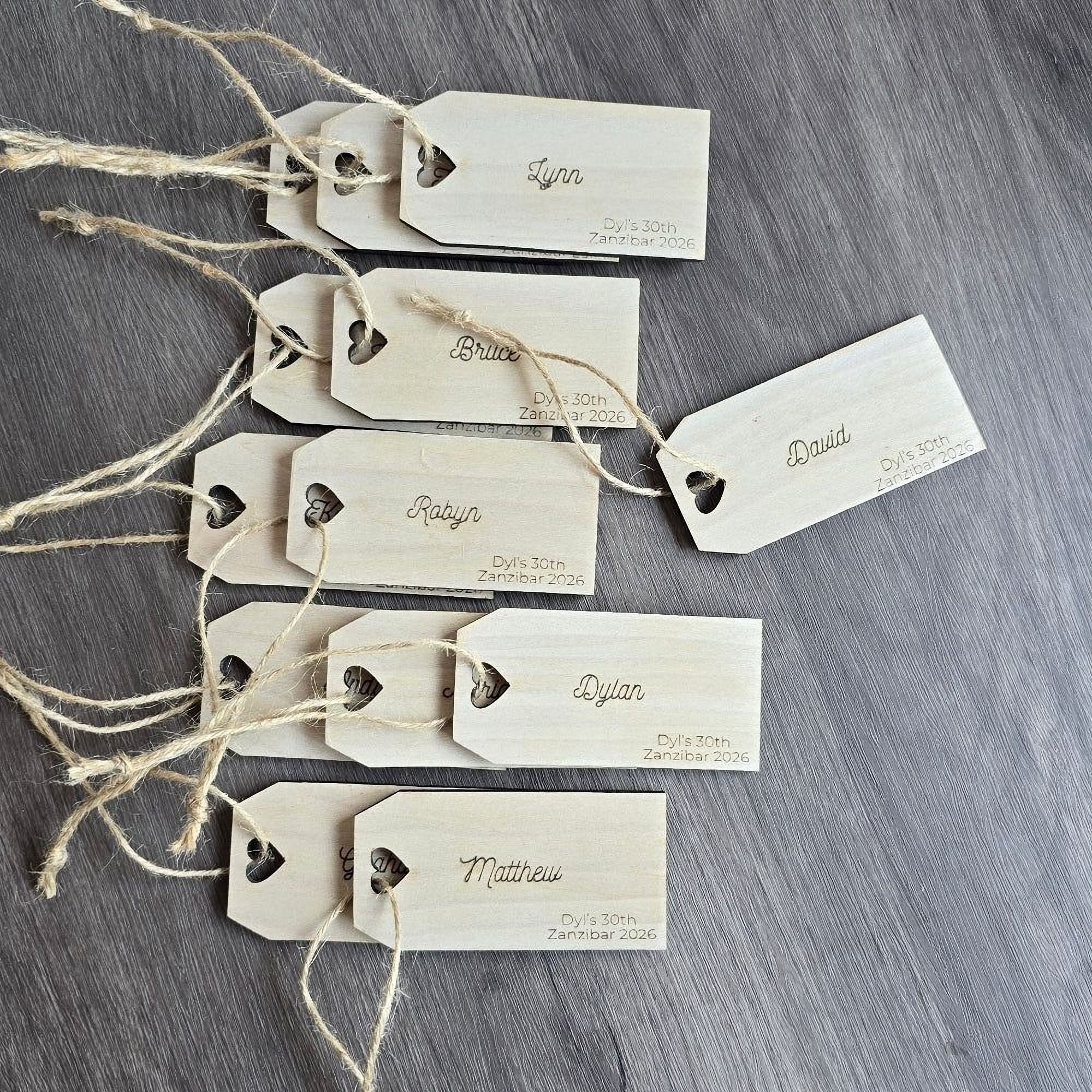 a collection of wooden name tags with names and dates printed on them, arranged on a wooden surface.