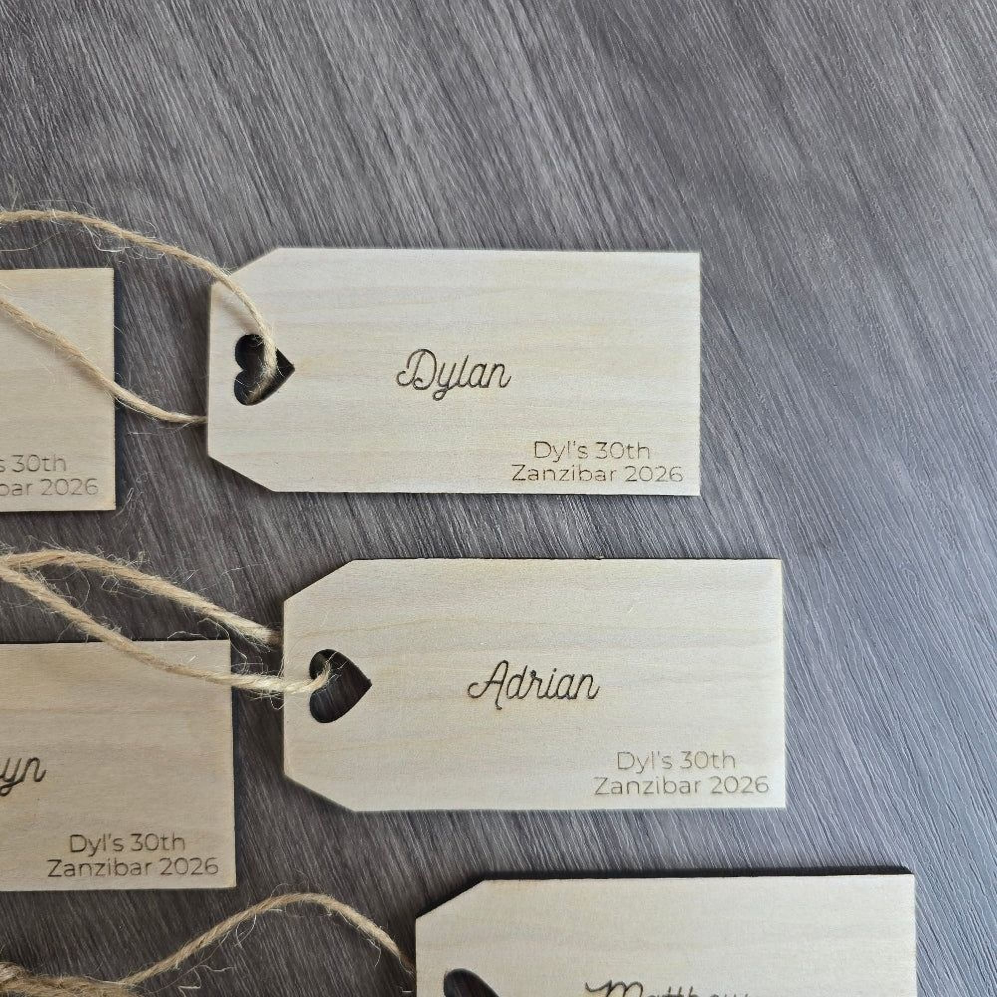 several wooden tags with names and dates printed on them, attached to a wooden surface.