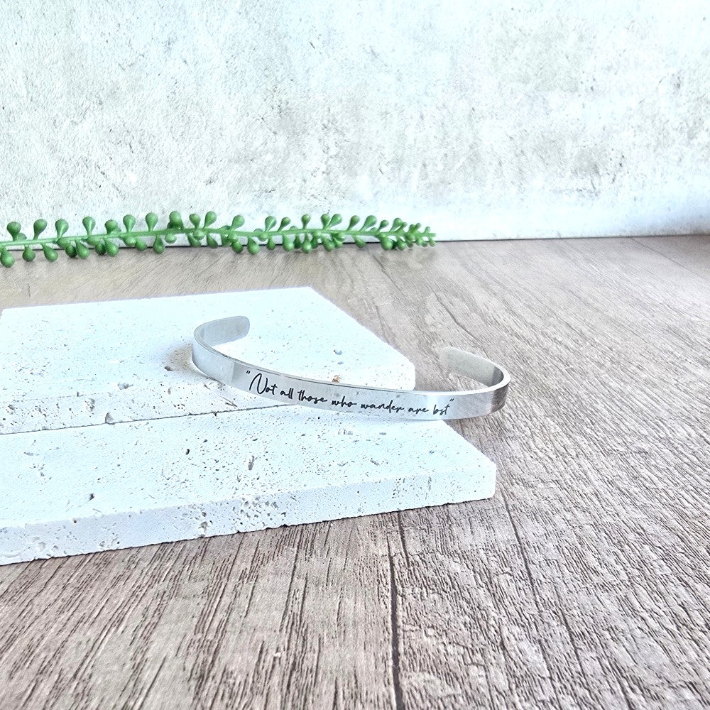 Silver bracelet with engraved text on a wooden surface