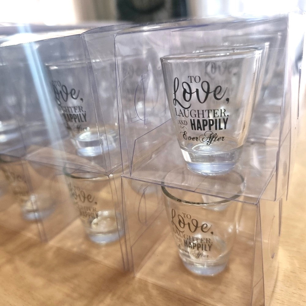 Set of shot glasses with printed text in a clear plastic display case.