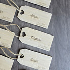a collection of wooden name tags with names and dates printed on them, arranged on a wooden surface.