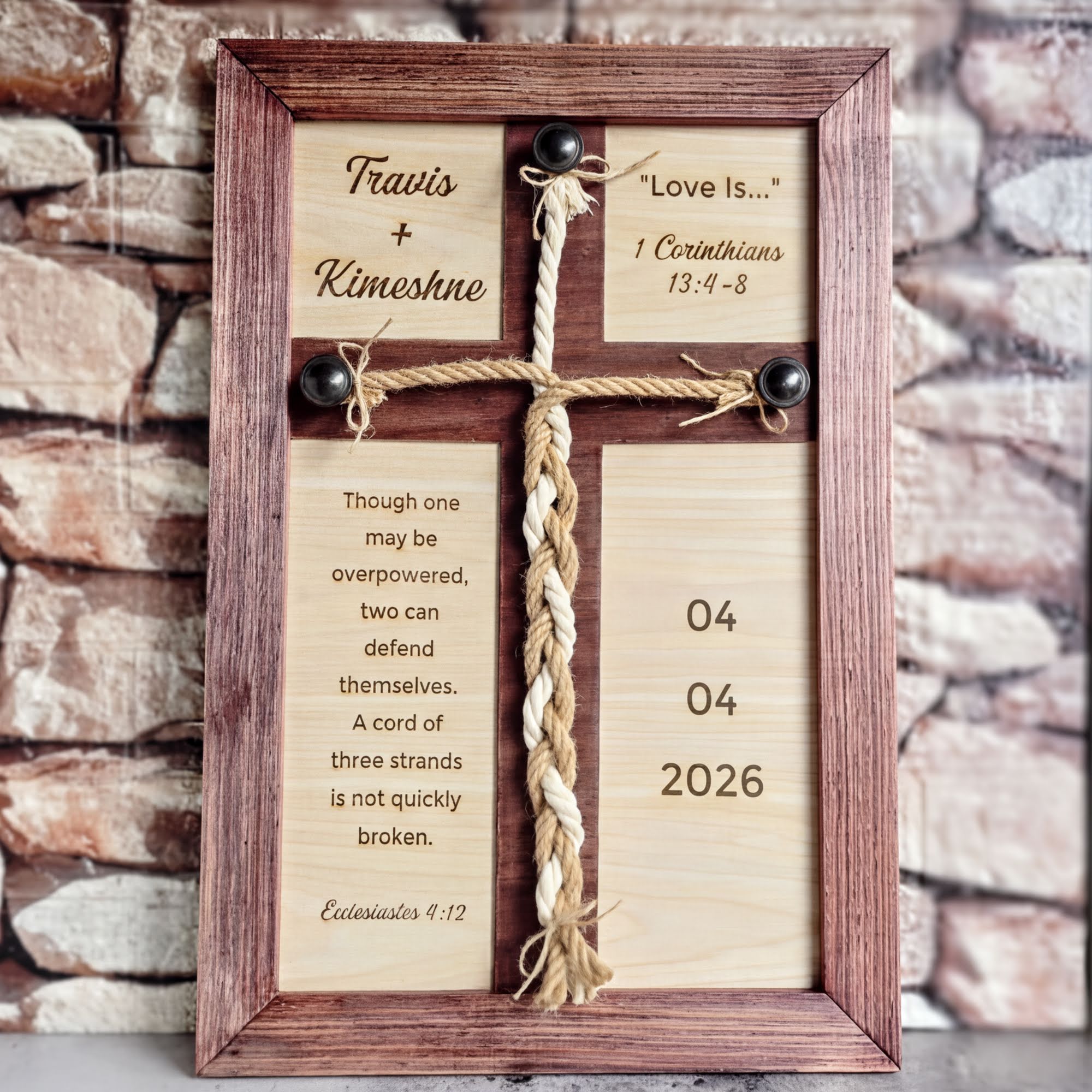 A wooden cross with a religious inscription and a date displayed on it, placed against a brick wall background.