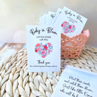 Baby shower thank you seed pack favours with floral designs on a woven surface