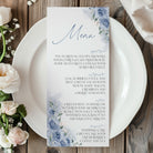 Menu card with floral design on a white plate with flowers on a wooden table