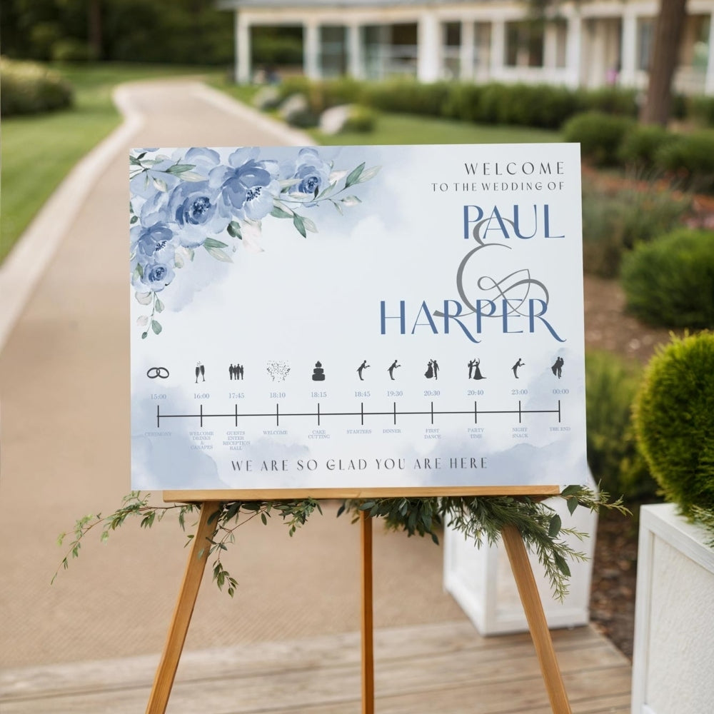 Wedding welcome sign with floral design and names on an easel outdoors.
