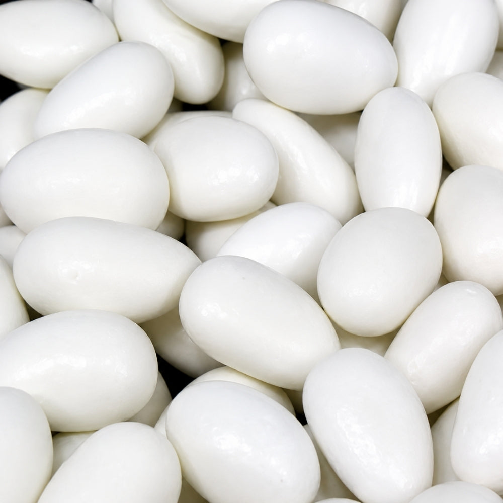 A close-up pile of smooth, glossy white sugar-coated almond candies filling the frame.
