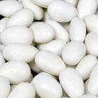 A close-up pile of smooth, glossy white sugar-coated almond candies filling the frame.