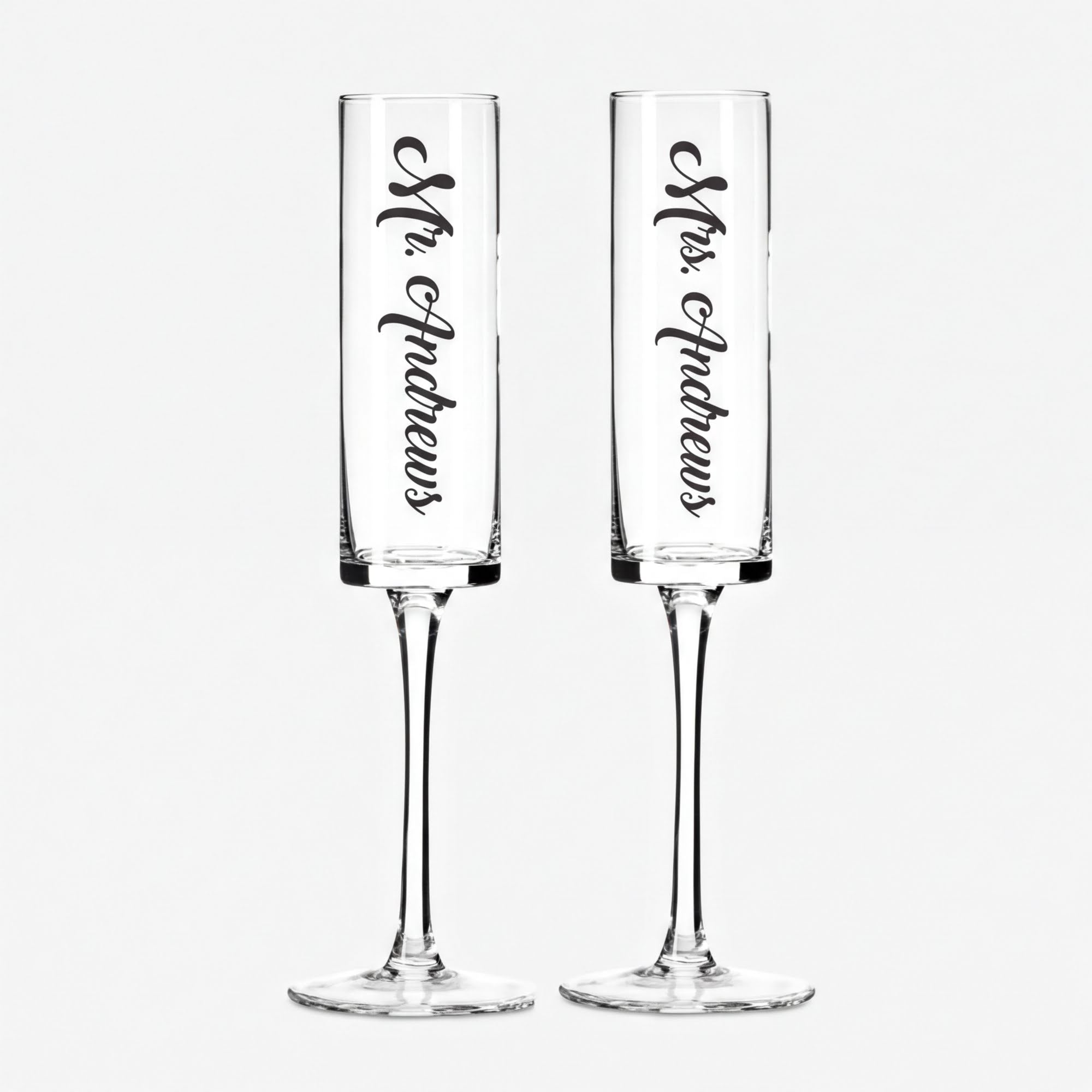 Two clear glass goblets with the names "Mr. Andrews" and "Mrs. Andrews" printed on them in a vertical orientation.