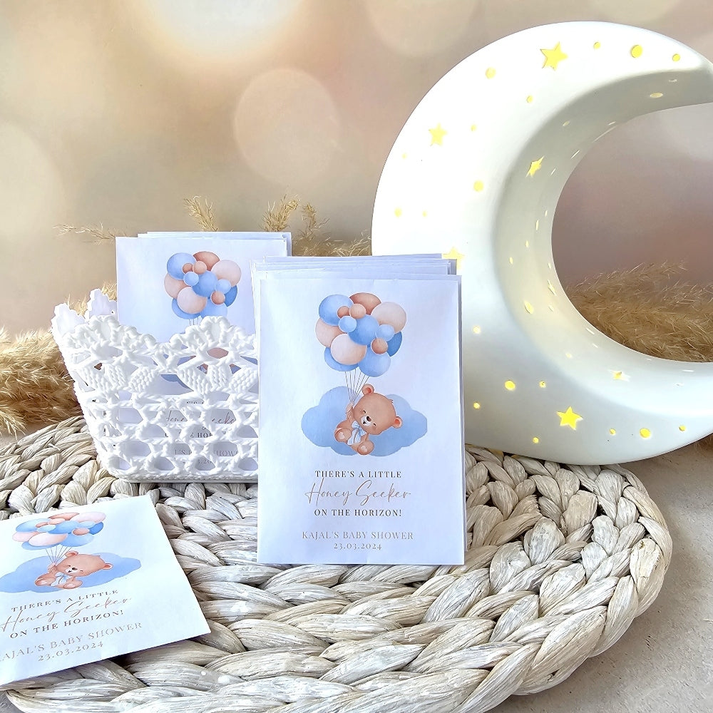 Baby shower thank you seed pack favours with teddy bear design on a textured surface with a moon lamp in the background.
