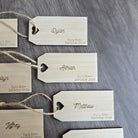 several wooden name tags with names and dates printed on them, attached to a wooden surface.
