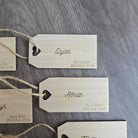 several wooden tags with names and dates printed on them, attached to a wooden surface.