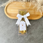 Gold spoon in a clear package with a white ribbon and tag