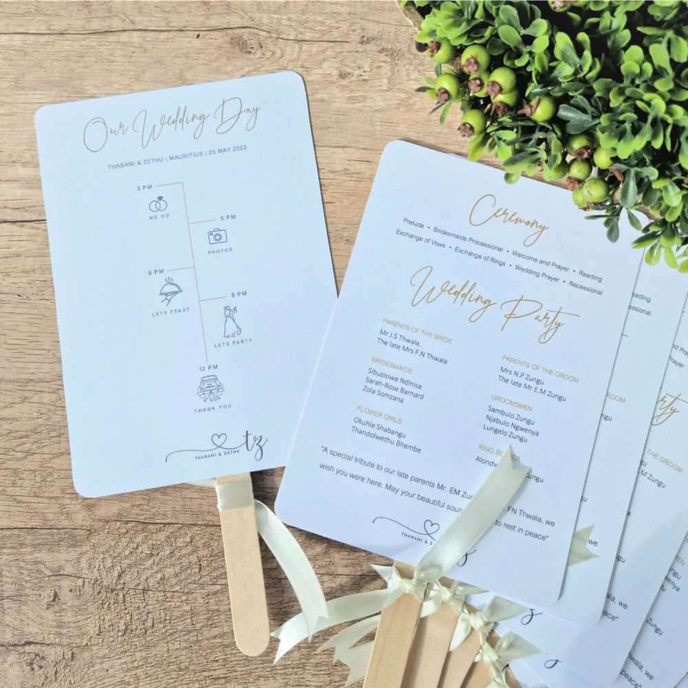 A fan program with a white background featuring text and a timeline diagram for a wedding ceremony. It is displayed with wooden sticks and decorative greenery in the background.