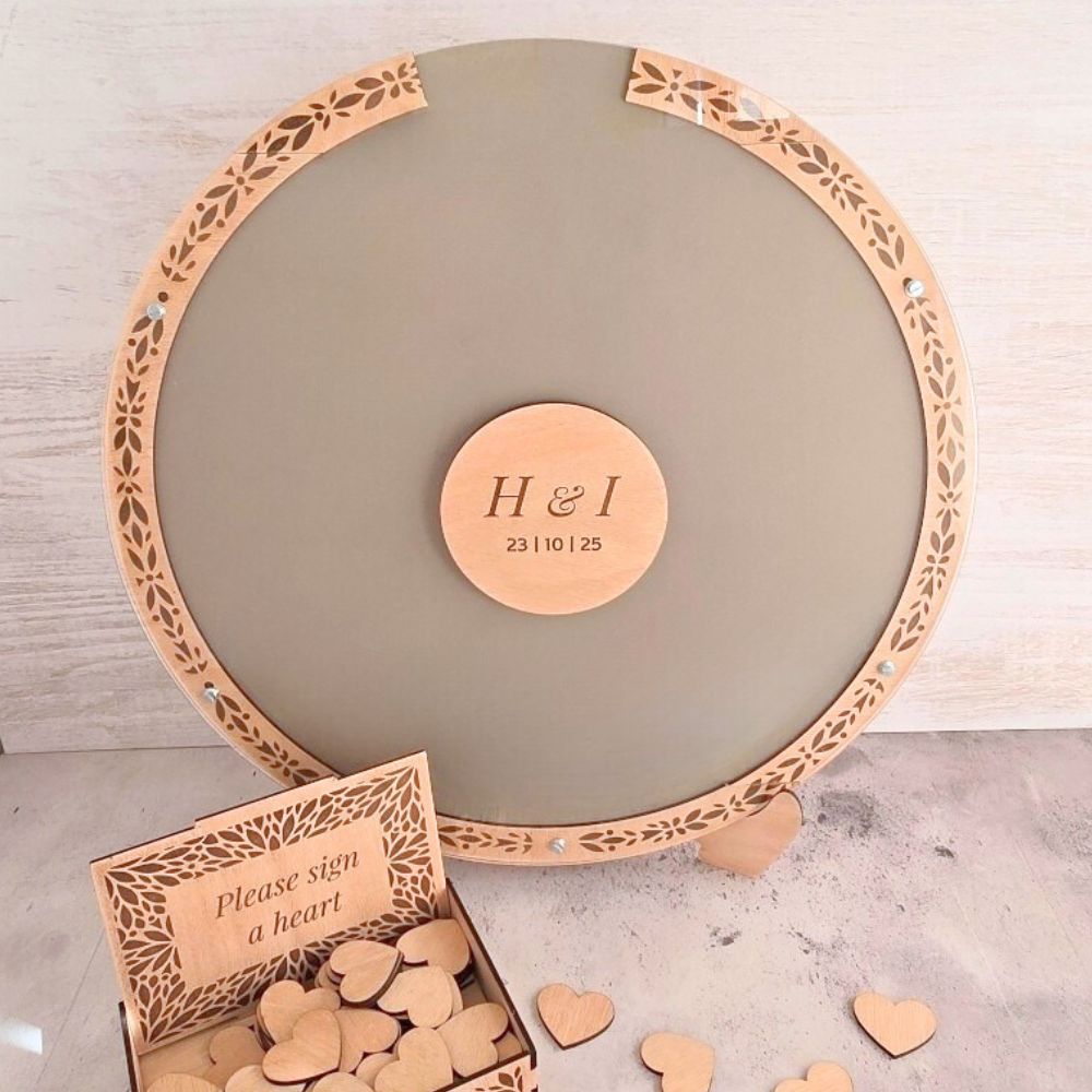 Round wooden board with laser-cut edge and 'H & I' stamp, accompanied by heart-shaped wooden pieces.